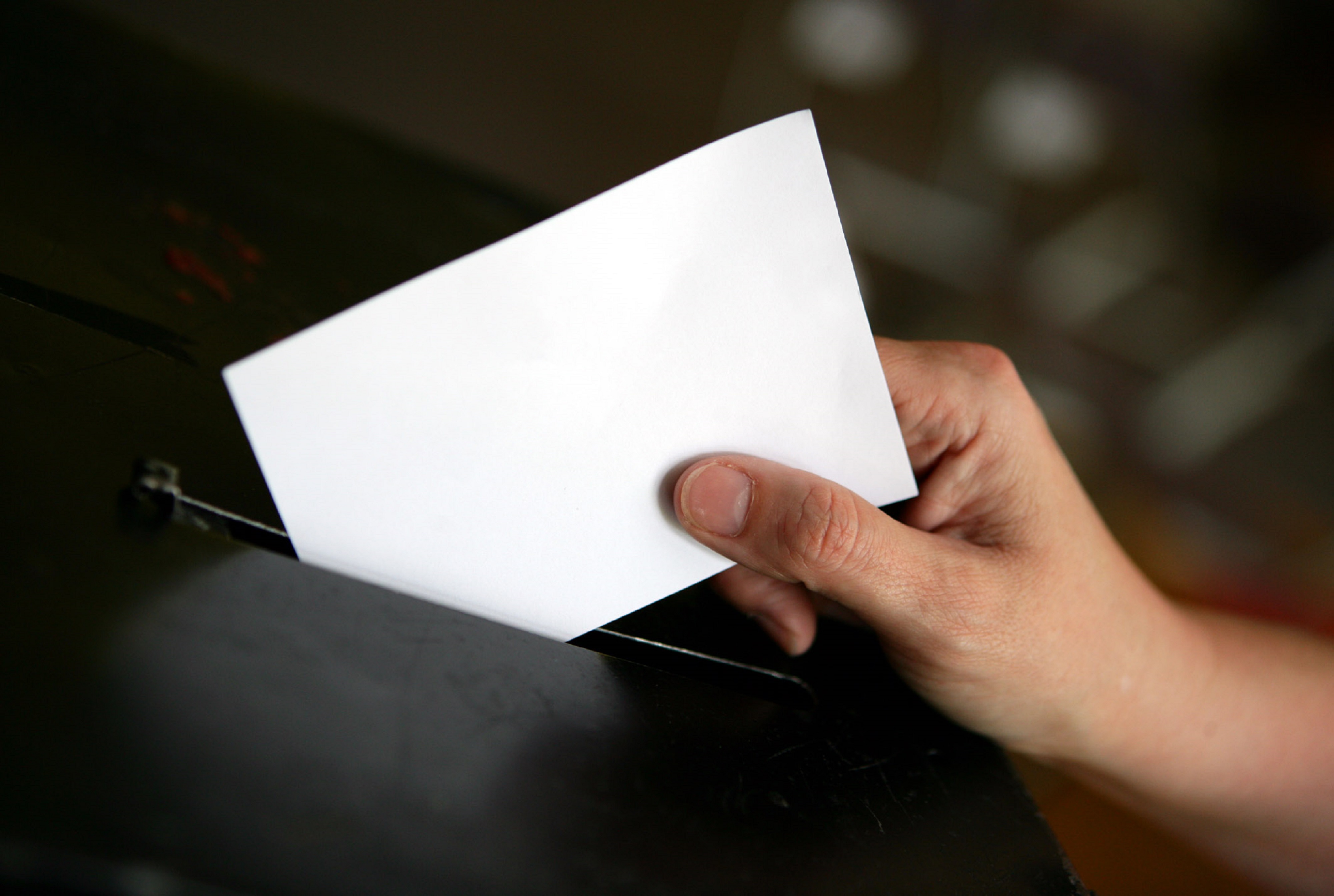 A person putting a ballot paper in a ballot box