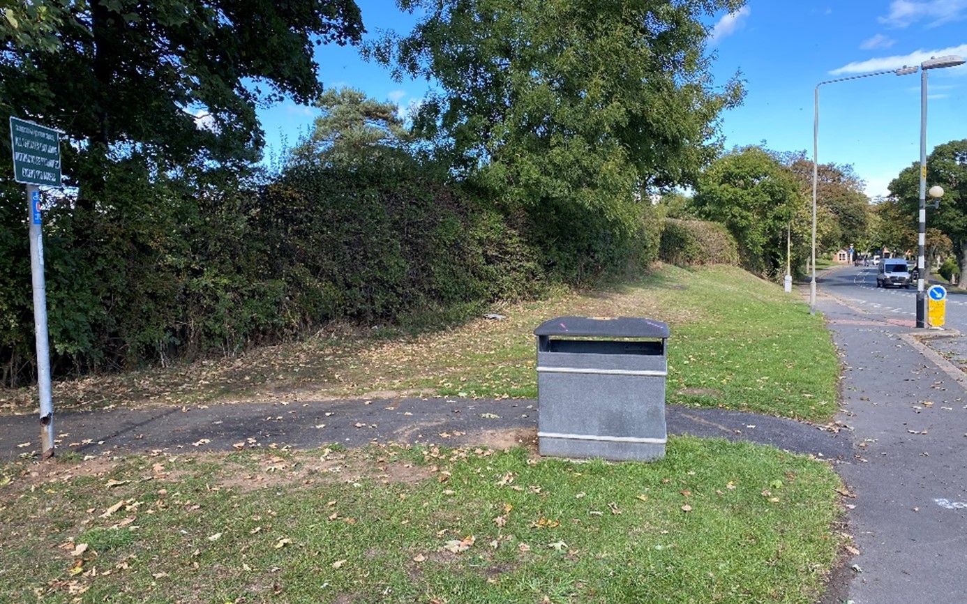 The entrance to the Cinder Track from Cross Lane, consisting of a small path and waste bin.