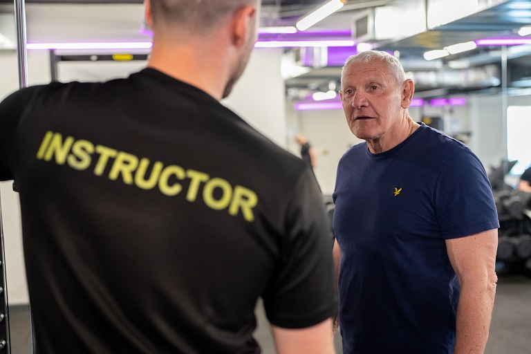 A gym member being given instruction by a personal trainer