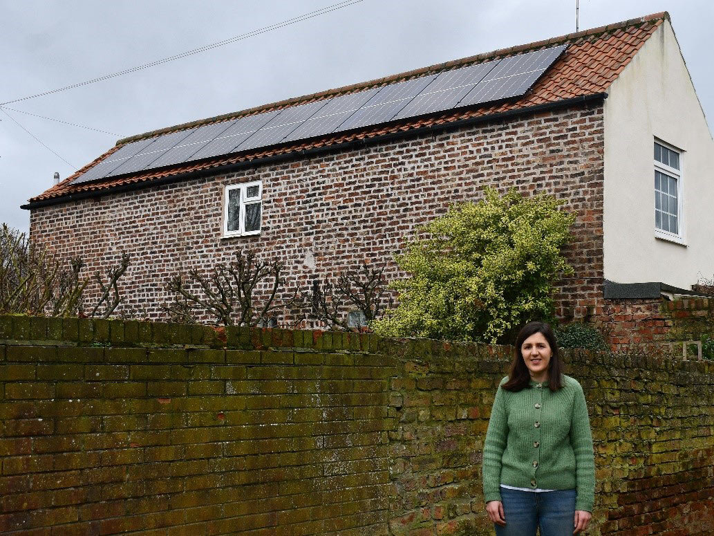 A lady in front of a house with solar panels