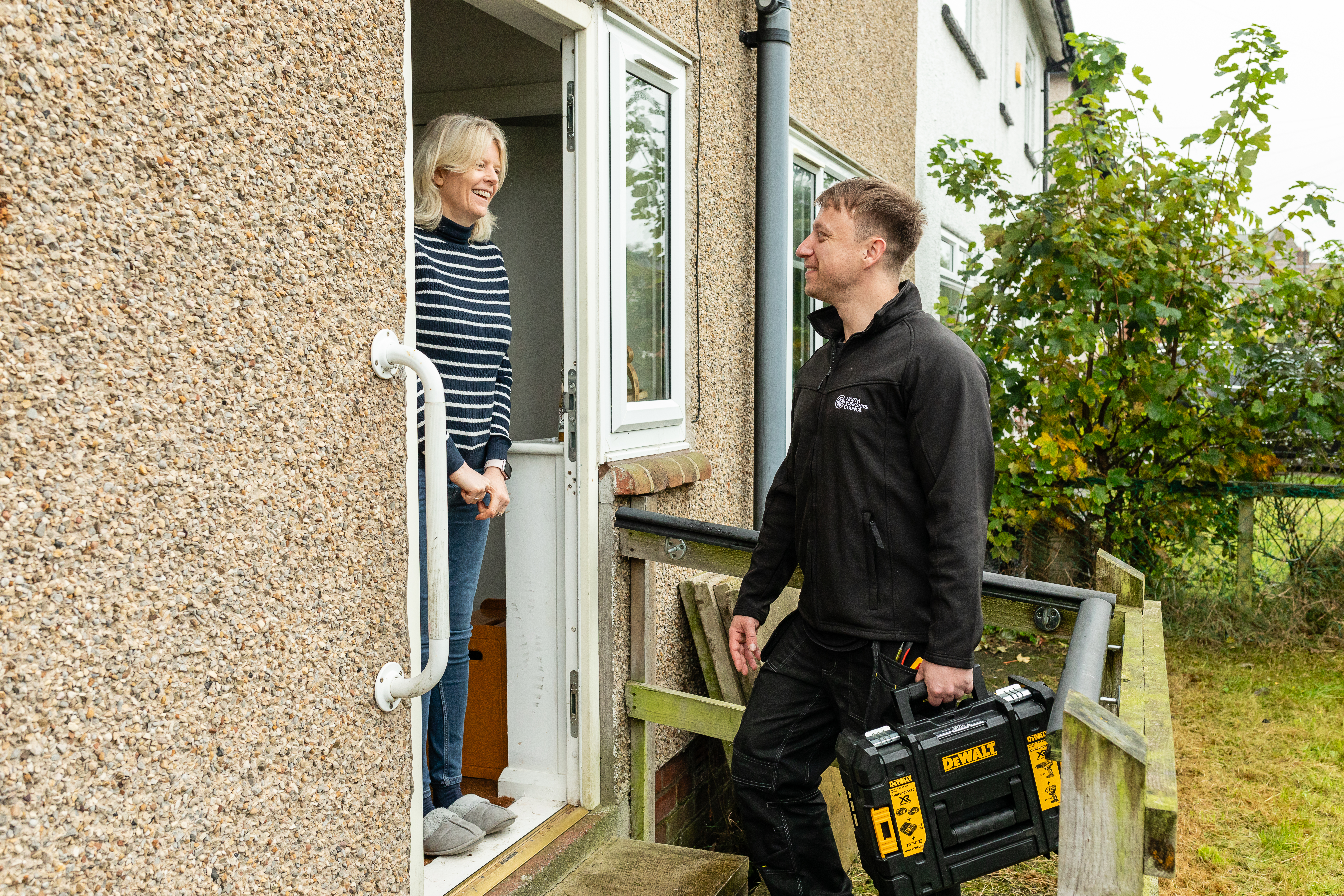 A workman talking to a lady on her doorstep