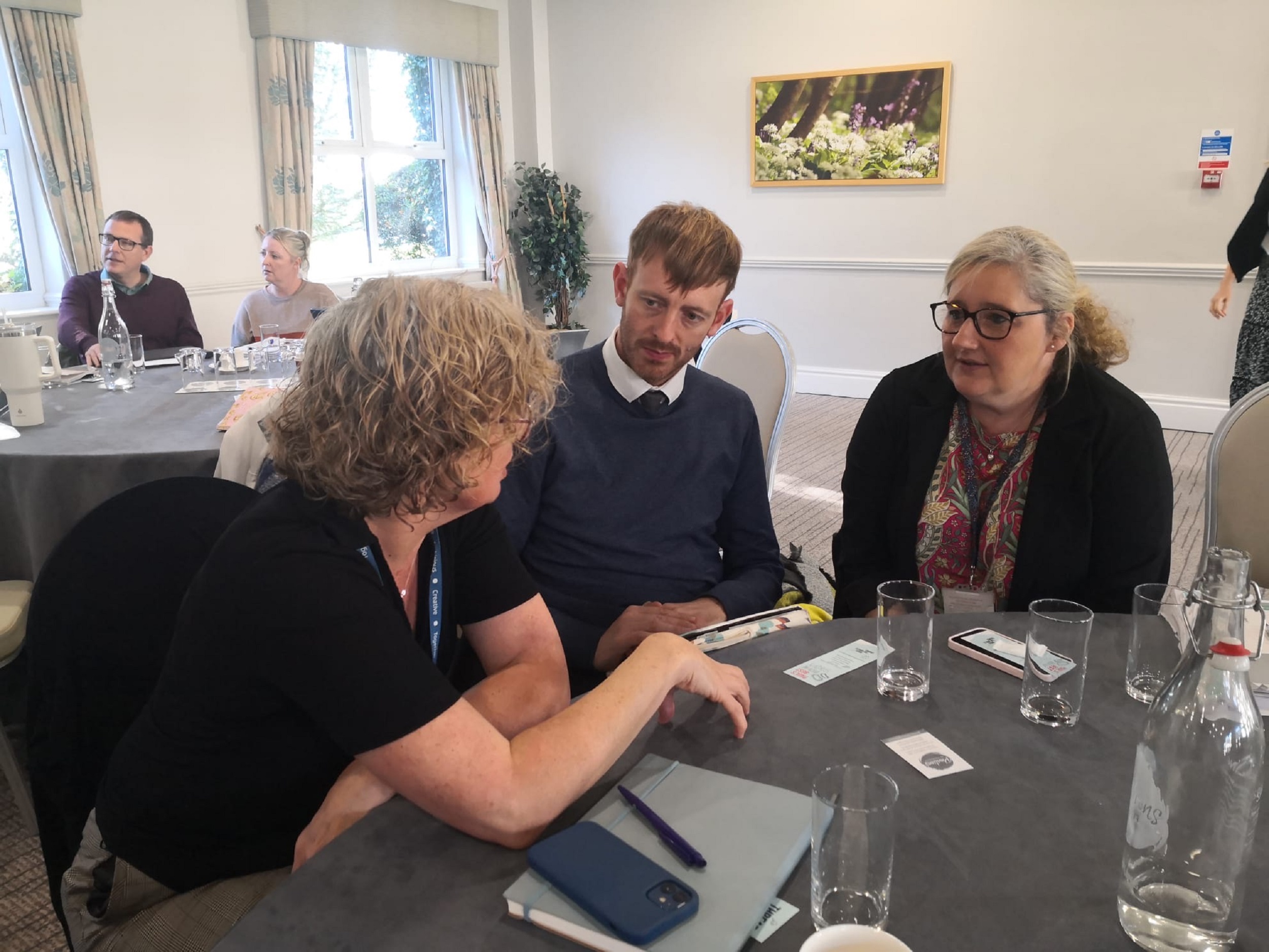 Three people sat at a table talking during an inclusion event