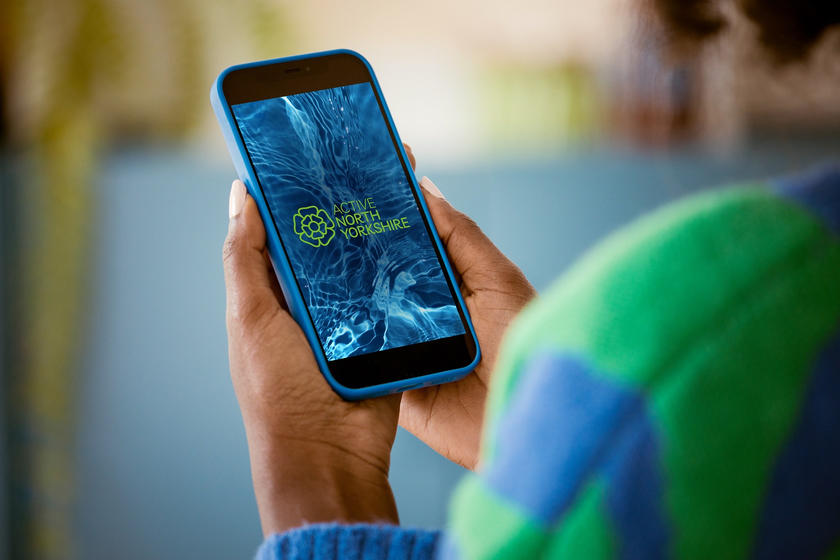 A person holding a mobile phone showing the Active North Yorkshire app loading screen