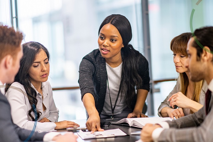 Group of five colleagues sat around a table looking at notes.