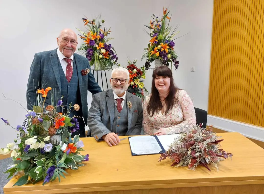 A married couple sat behind a desk after signing the register