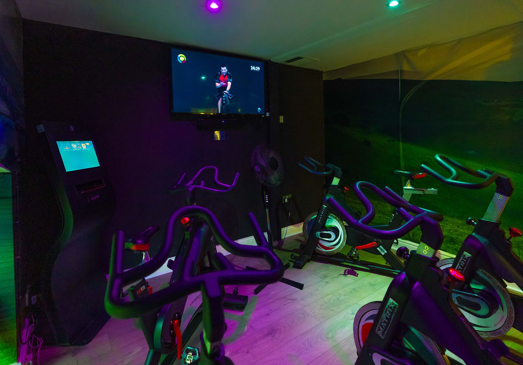 The spin class room at Richmond Leisure and Wellbeing Hub with exercise bikes and virtual trainer on a screen.