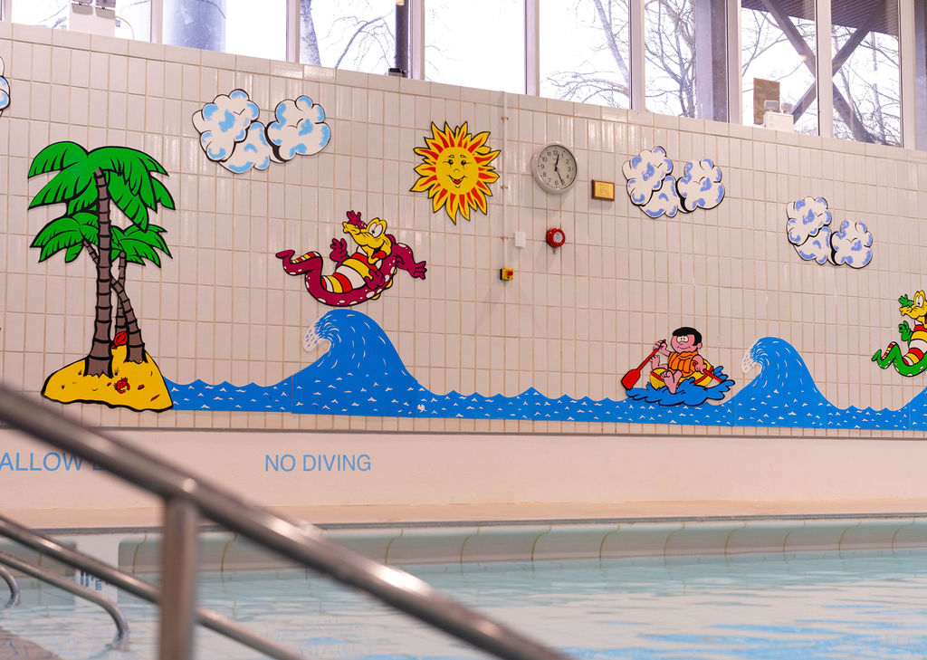 The wall beside Richmond Leisure and Wellbeing Hub featuring a mural of cartoon people and animals having fun in the sea.