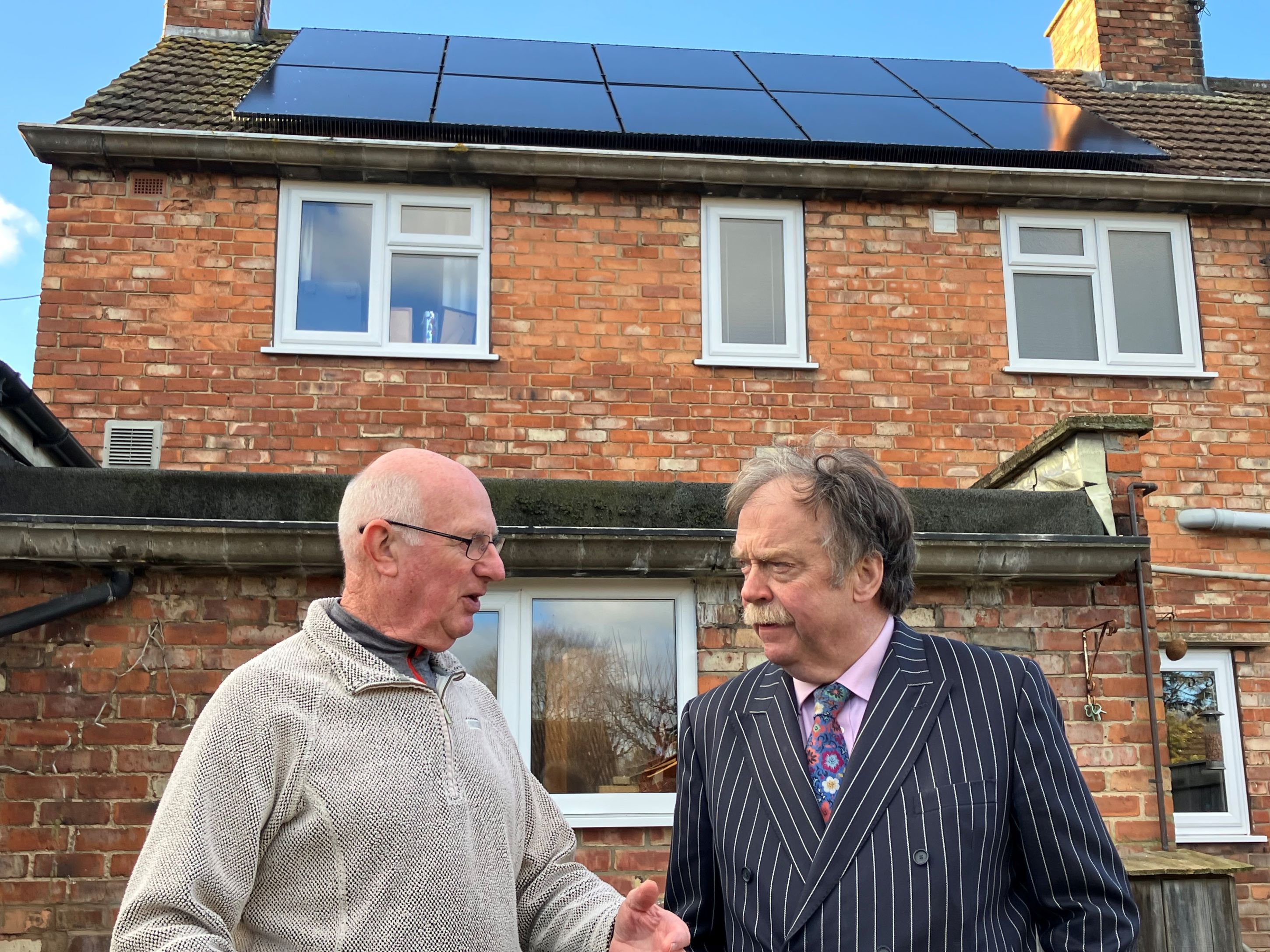 Two men in front of a house with solar panels