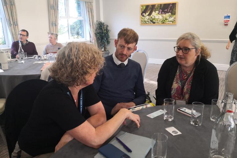 Three people sat at a table talking during an inclusion event