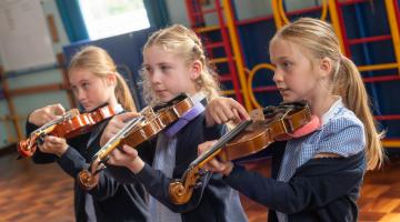 Learning to play the violin are pupils Lyla Everleigh, Darcey Wilmer and Jasmine Everleigh.