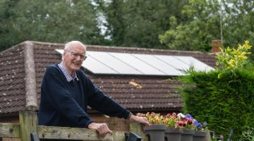 Geoffrey Evans in front of a house with solar panels