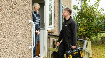 A workman talking to a lady on her doorstep