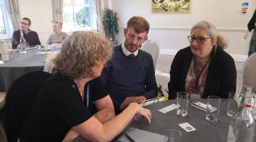 Three people sat at a table talking during an inclusion event