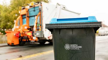 A recycling bin in front of a bin lorry