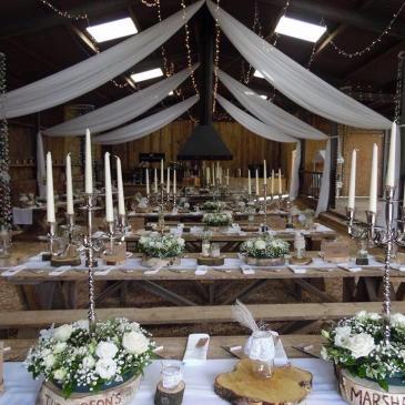 Open barn space laid out with table rows ready for a wedding dinner.
