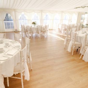 Tables and chairs set up for a wedding dinner in a marquee. 