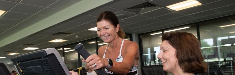 A woman on a cross trainer with a gym instructor