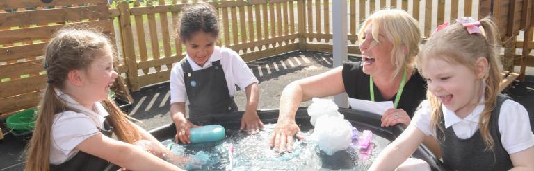 School children and teacher playing with water