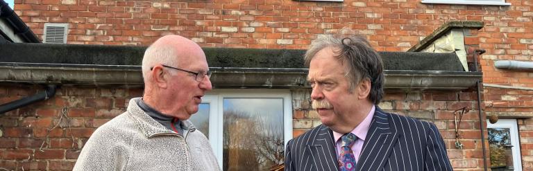 Two men in front of a house